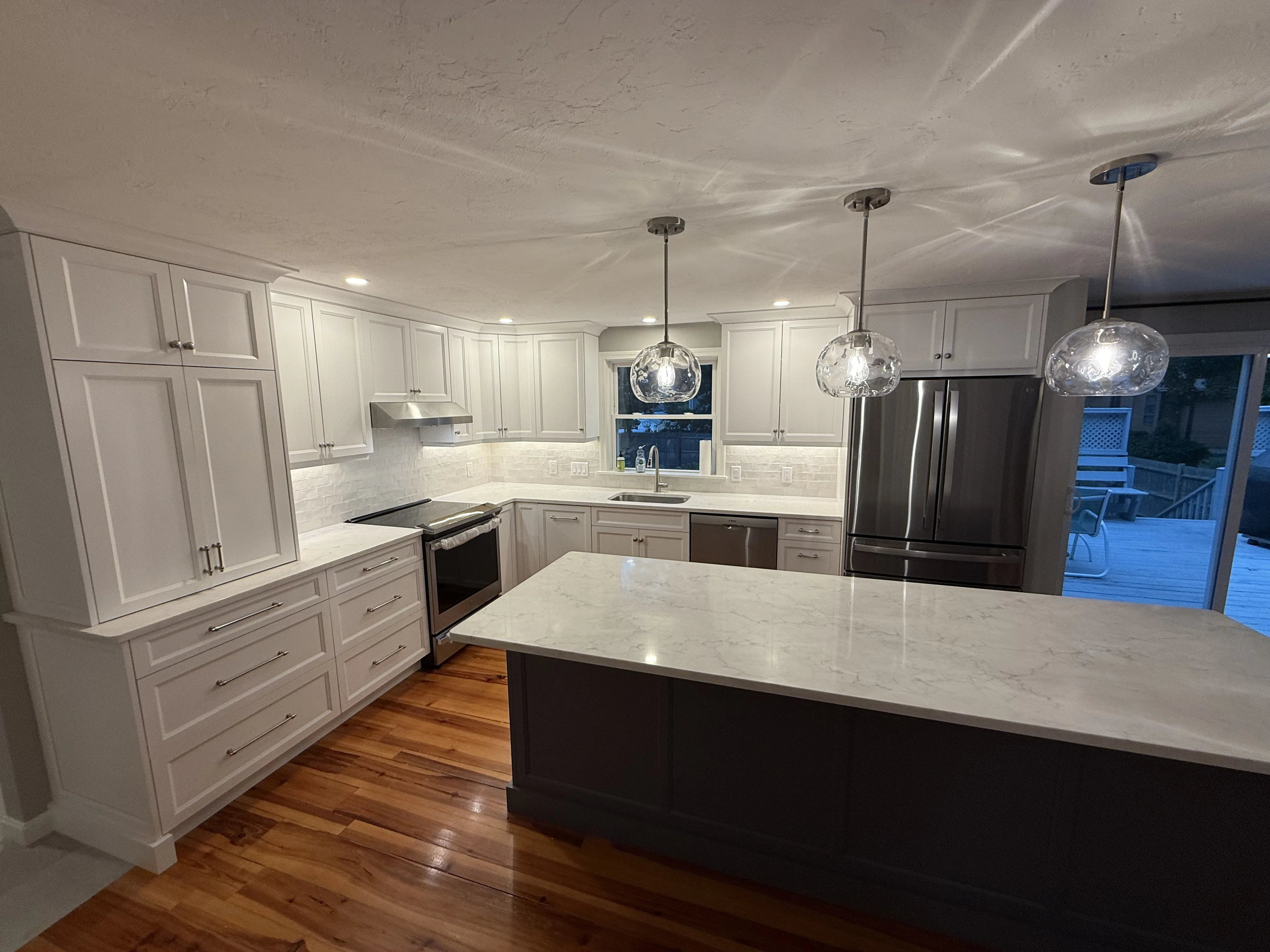 Recently remodeled kitchen in Taunton, MA with pendant lighting over the island, recessed cans, and quartz countertops